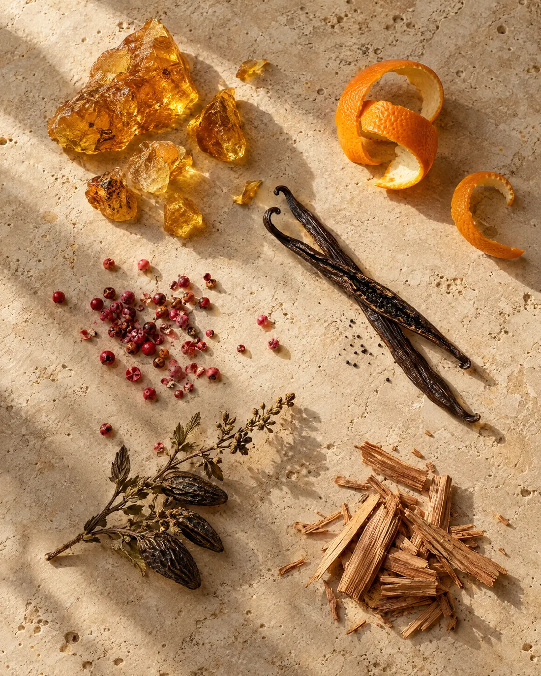 Amber resin, orange peel, vanilla pods and pink peppercorns on warm travertine.