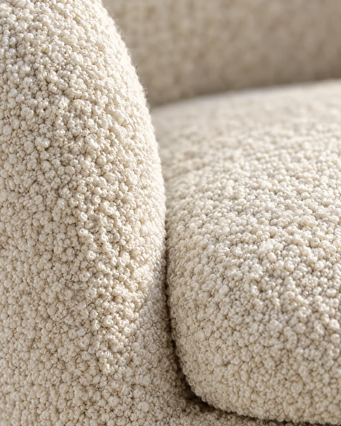 Close-up of the cream bouclé loops where the arm meets the seat.
