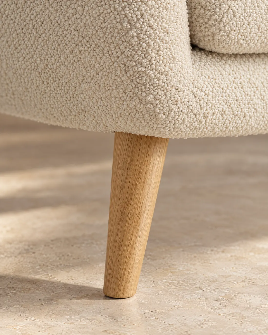 A tapered solid oak leg with visible grain under the chair.