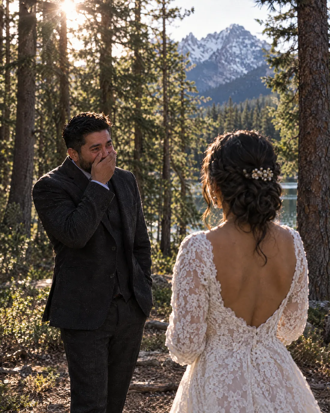 In a pine forest, the groom turns and sees the bride for the first time, his hand over his mouth.